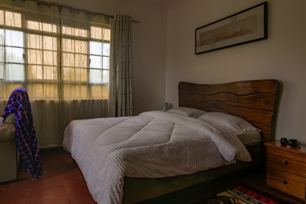Impala room at Wadich — cozy bedroom with carved wooden headboard and Maasai shuka accents